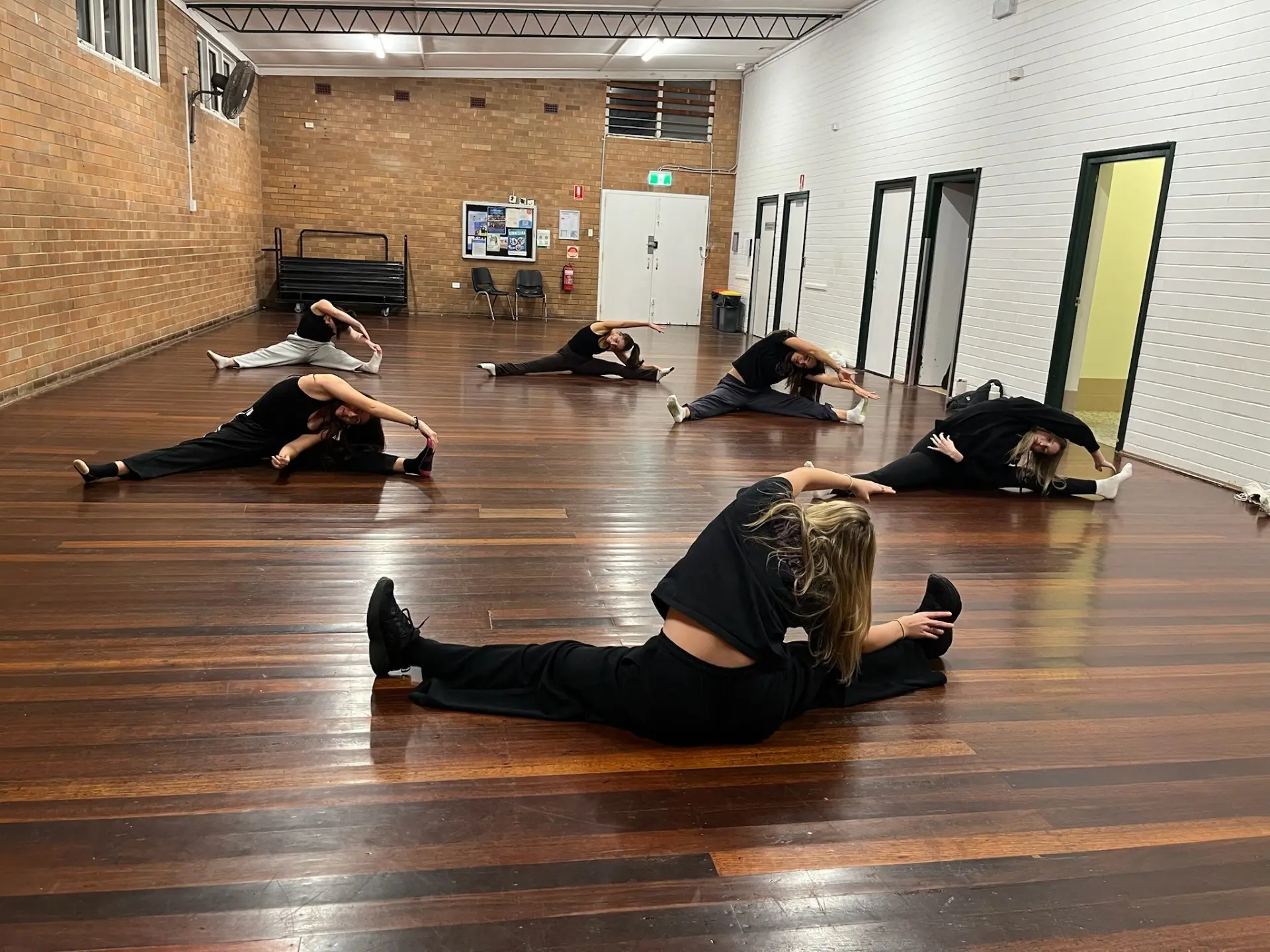 NoCo dancers in a wide floor stretch across the timber hall floor
